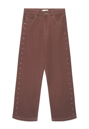 Pantaloni marroni a gamba larga con borchie argentate sui lati, chiusura frontale con bottone e zip e tasche frontali e posteriori.