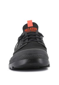Sneaker neri con tomaia texturizzata e suola in gomma spessa. Presenta una linguetta rossa prominente sul tallone e lacci neri.