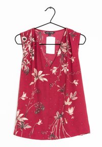 Blouse rouge sans manches avec un décolleté en V, présentant un motif floral dans des tons crème et vert, fabriquée à partir d'un tissu léger.