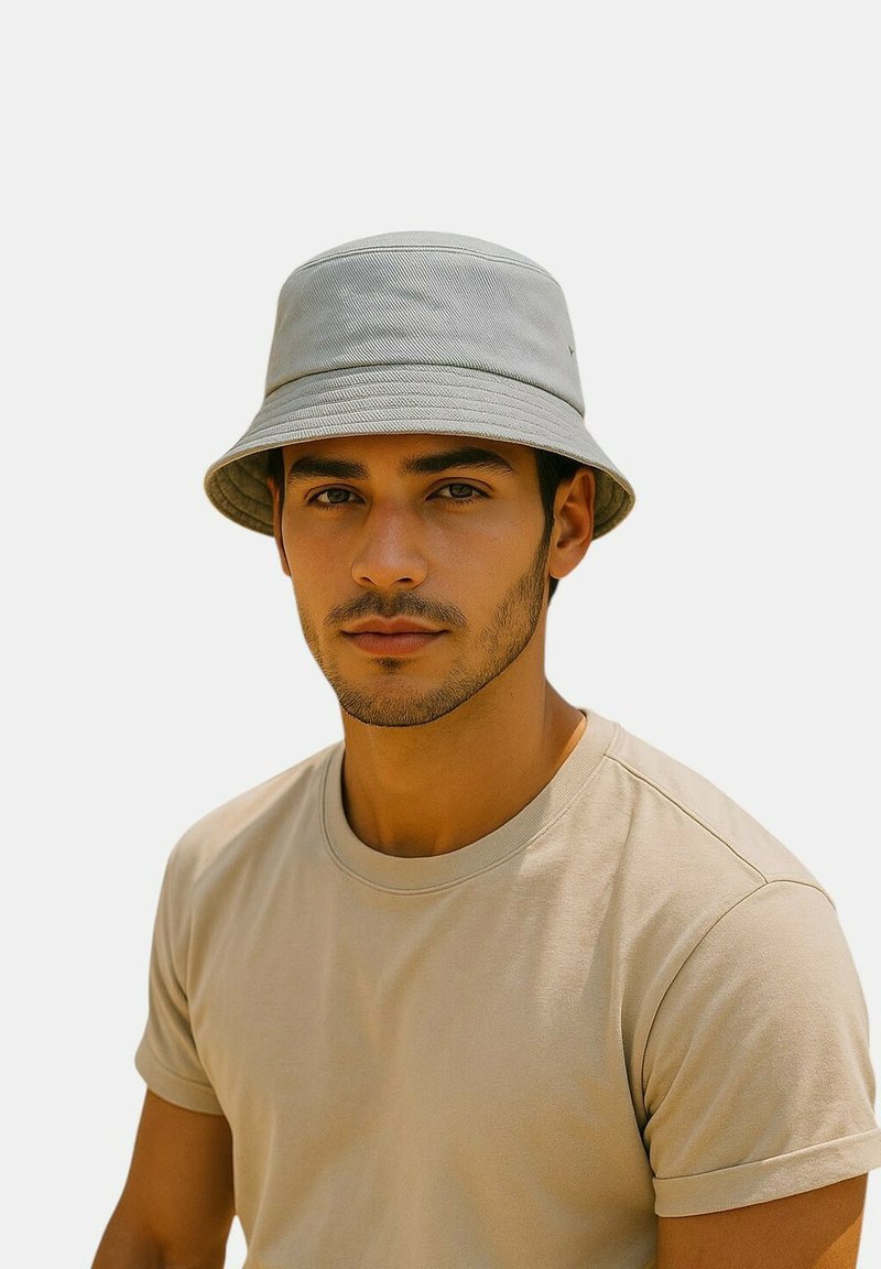 Grauer Bucket-Hut aus weichem Stoff mit breiter Krempe und dezentem Muster, kombiniert mit einem schlichten beigen T-Shirt.