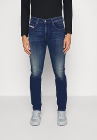 Mörkblå denimjeans med slim fit, blekt fram, klassisk femficksdesign och subtila stickningsdetaljer. Matcha med grå sneakers.