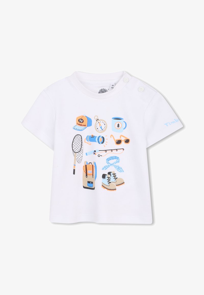 T-shirt blanc à manches courtes avec des illustrations imprimées colorées d'équipements de plein air, comprenant une casquette, une montre, un sac à dos, une raquette de tennis et des lunettes de soleil.