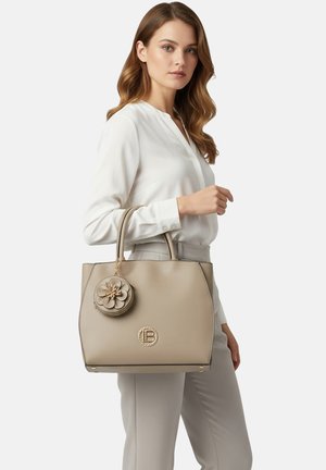 Borsa a tracolla in pelle beige con doppio manico, caratterizzata da un accento floreale e logo in rilievo sulla parte anteriore. Design strutturato e texture liscia.