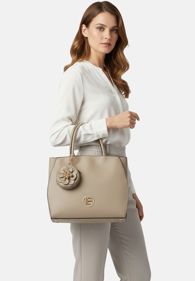 Borsa a tracolla in pelle beige con doppio manico, caratterizzata da un accento floreale e logo in rilievo sulla parte anteriore. Design strutturato e texture liscia.