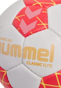 Træningsfodbold med hvid og rød design, der har geometriske mønstre, struktureret overflade og gule accenter. Brandlogo synligt.