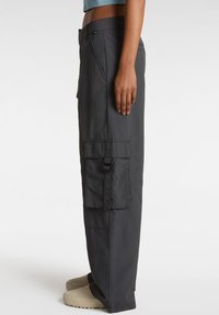 Pantaloni cargo grigi con vestibilità ampia, dotati di una grande tasca laterale e dettagli con fibbia. Tessuto liscio e leggero con finitura opaca.