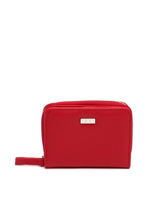 Cartera pequeña roja con cremallera, correa para la muñeca y un pequeño detalle metálico rectangular plateado en la parte delantera.