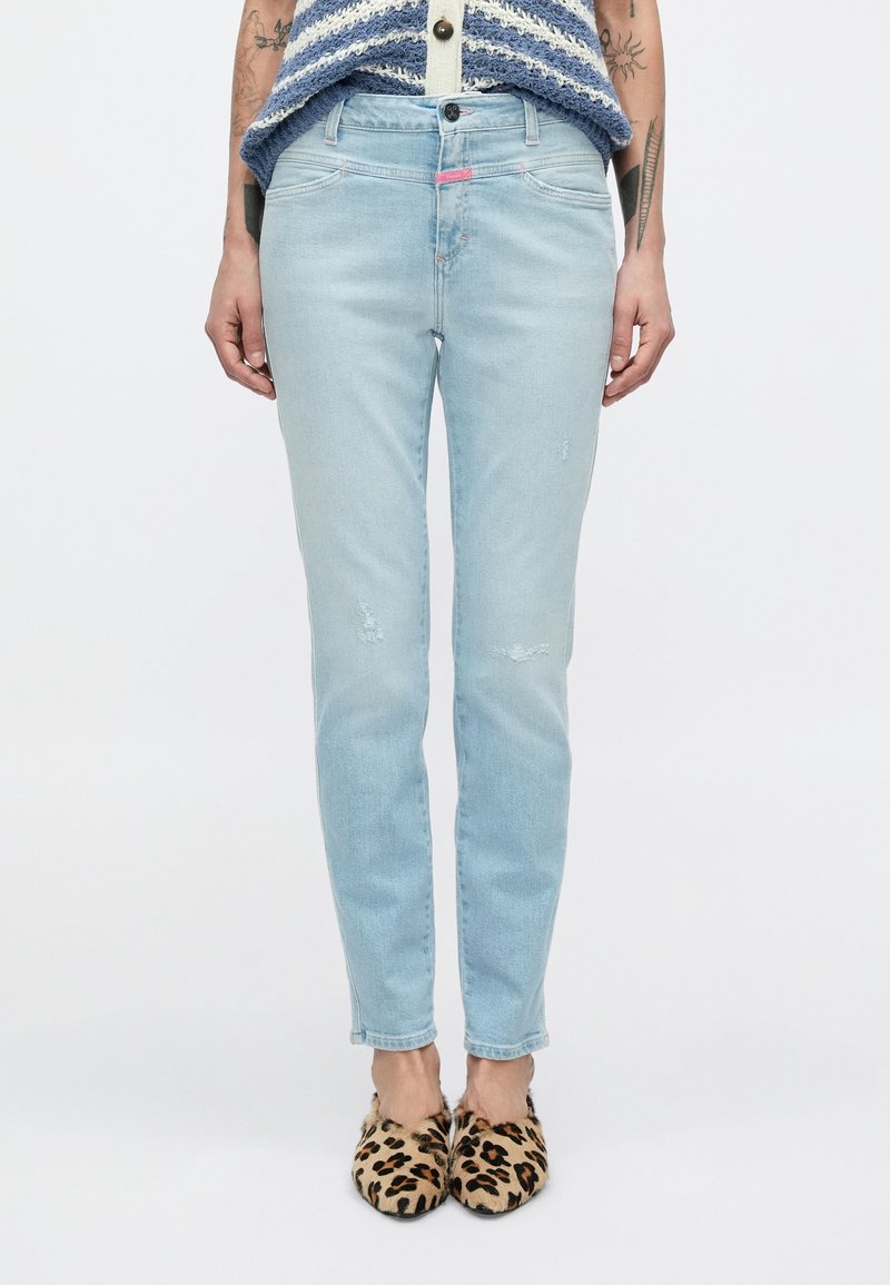 Ανοιχτό μπλε τζιν στενής εφαρμογής με φθαρμένες λεπτομέρειες. Κατασκευασμένο από ντένιμ, διαθέτει κλείσιμο με κουμπί και διακριτικές ροζ λεπτομέρειες στη μέση.