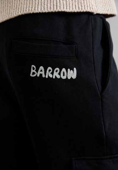 Pantaloni sportivi neri con una tasca posteriore e la parola "BARROW" ricamata in grigio chiaro. Il tessuto sembra morbido e testurizzato.