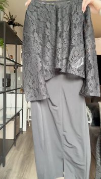 Top en dentelle noire avec une coupe ample sur une jupe lisse de couleur gris foncé. Les caractéristiques clés incluent des motifs floraux délicats et une texture de tissu fluide.