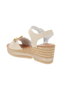 Sandali wedge beige con piattaforma in paglia testurizzata, cinturino regolabile e fiocco decorativo, dotati di tomaia in pelle liscia e soletta imbottita.