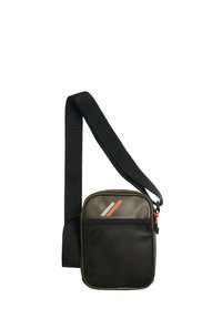 Oliwkowa torba na ramię z czarną siatkową przednią kieszenią. Posiada czarny regulowany pasek, czerwoną zawieszkę zamka oraz geometryczne akcenty designu.
