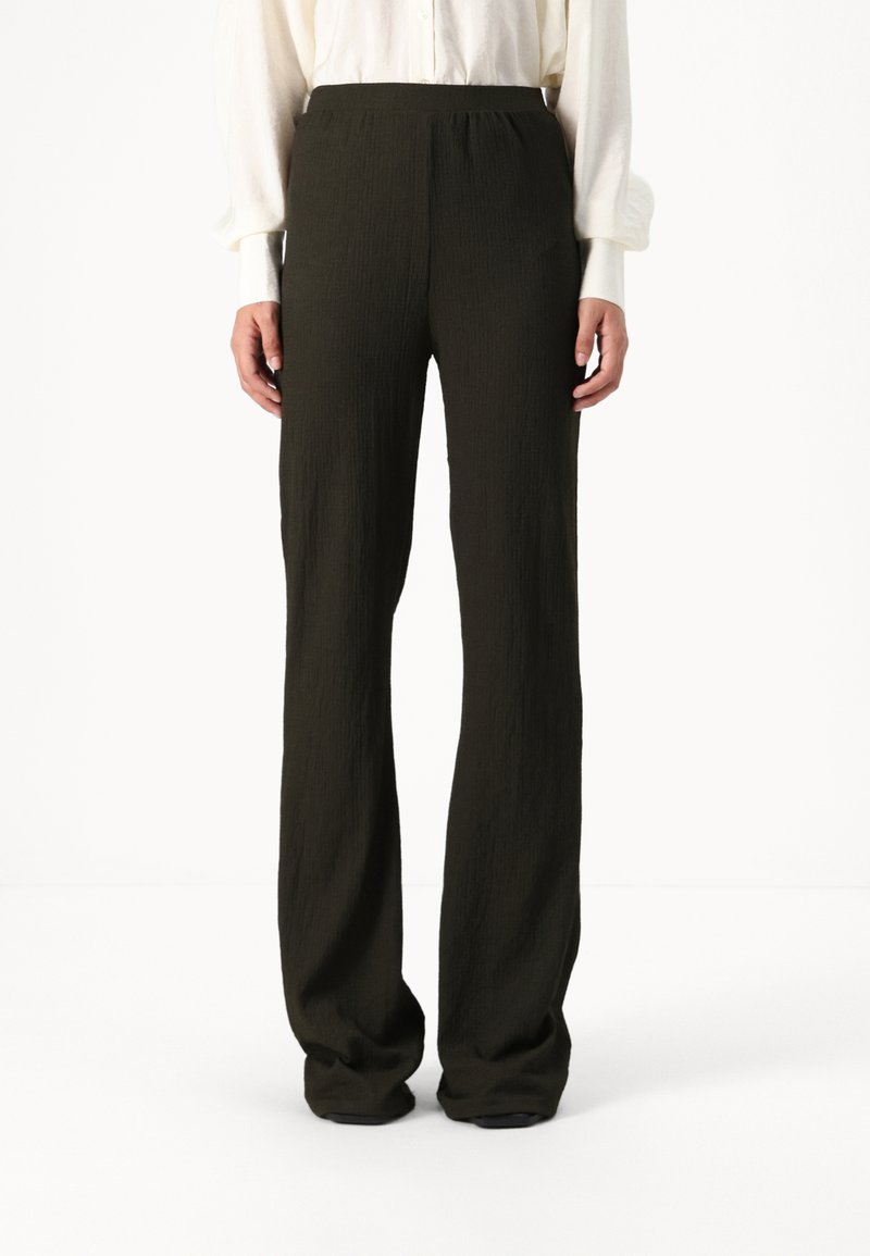 Dark green, textured wide-leg trousers with a high waist, featuring a smooth, elastic waistband and no visible hardware.