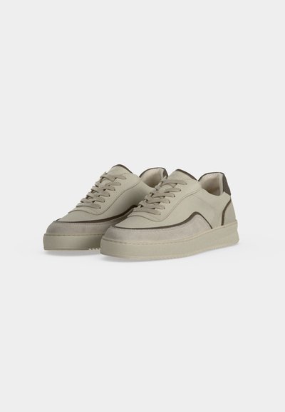 Paire de baskets basses beige avec un design à lacets et une semelle texturée, avec une bande d'accent plus foncée le long du côté.