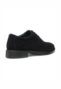 Scarpa stringata in suede nera con punta tonda e suola in gomma nera rigata. Caratterizzata da cuciture tonali e una linea superiore liscia.