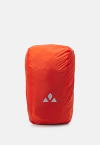 Mochila impermeable roja con textura suave, parte superior redondeada y acento de logo plateado. Diseño compacto adecuado para uso al aire libre.