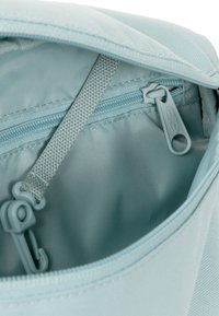 Interno di una borsa di tessuto blu chiaro caratterizzato da una superficie liscia, chiusura con zip e una zip blu chiaro con linguetta di apertura.
