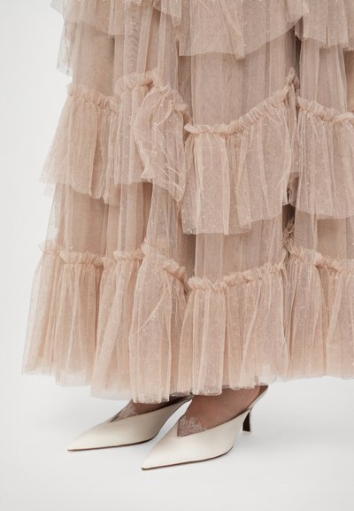 Kerge roosa kihiline tüllseelik, mille servadel on volangid, koos valgete terava toe kontsadega, millel on pitsidetailid.