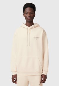 Felpa beige con cappuccio realizzata in tessuto morbido; presenta una tasca a marsupio e un logo discreto sul petto. Disponibile in vestibilità rilassata.