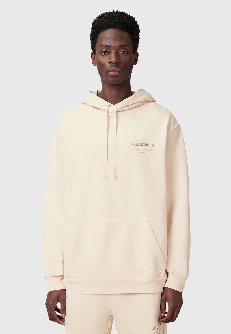 Felpa beige con cappuccio realizzata in tessuto morbido; presenta una tasca a marsupio e un logo discreto sul petto. Disponibile in vestibilità rilassata.