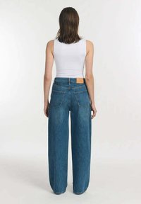 Hoge taille, wijde jeans in middelblauwe denim. Bevat een leren label op de achterkant van de tailleband en twee achterzakken.