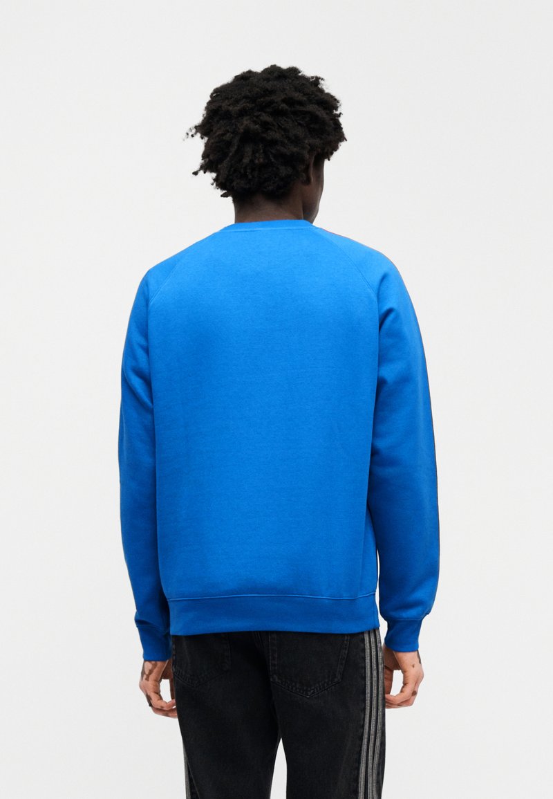 Sweat-shirt bleu à col rond, manches longues et poignets côtelés. Confectionné en tissu doux, avec une texture lisse et sans motifs visibles.