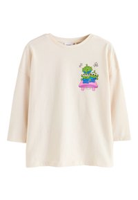 Cream-colored short-sleeve t-shirt made of cotton, featuring a graphic of three cartoon aliens on a pink table, with sparkling accents.