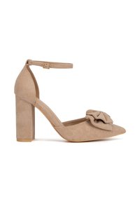 Zapato de tacón alto de ante beige con punta puntiaguda, detalle de volante de tela en el empeine y correa al tobillo con hebilla; acabado mate texturizado.