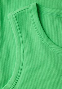 Top verde a costine disposti piatti, che mostrano una texture liscia, scollature rotonde e cuciture impeccabili, con diverse tonalità di tessuto verde.
