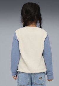 Sudadera de cuello redondo con cuerpo color crema y mangas azul claro; tela de algodón suave con puños acanalados; cuenta con una etiqueta cosida en la parte posterior.