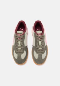Zapatillas de ante verde y gris con acentos en rosa, paneles de tela texturizada, cierre de cordones y suela de goma. Presenta el logotipo de Puma en la lengüeta.