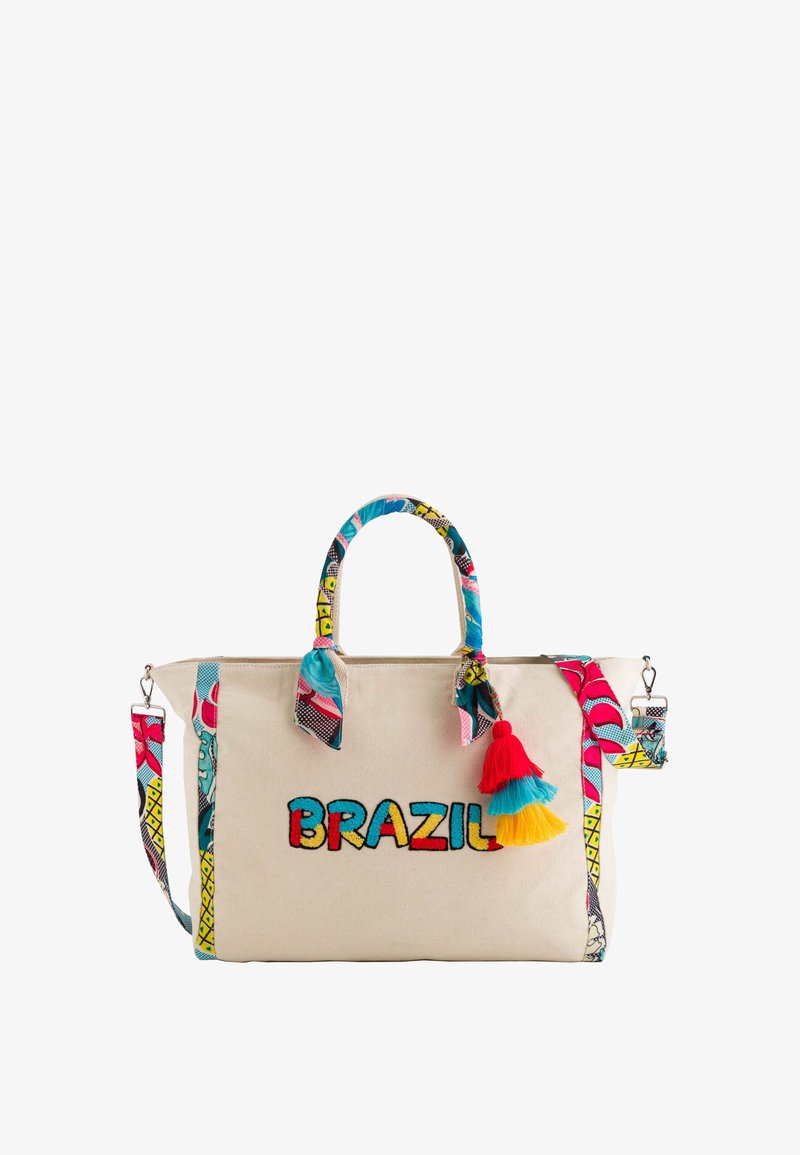 Canvas tote bag in cream with colorful embroidered "BRAZIL" text. Features patterned handles and a decorative tassel in red, blue, and yellow.