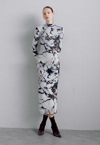 Form-fitting dress with a long silhouette. Made of soft fabric showcasing a marble pattern in gray, black, and subtle pink hues.