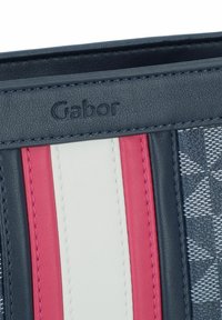 Gabor Geldbörse mit einem strukturierten dunkelblauen Stoff, akzentuiert mit pinken, weißen und dunkelblauen Streifen, geprägtem Logo und kontrastierenden Nähten.