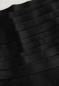 Banda elastice negre cu textul "NEXT" și accente de inimă într-un model repetitiv, având o textură netedă și un design plat.
