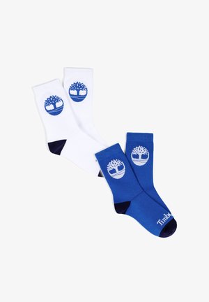 Twee paar enkelsokken, één wit en één blauw, elk met een boomlogo op de enkel en zwarte accenten op de teen en hiel.
