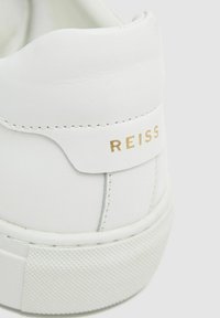 Fehér bőr sneaker, textúrált gumitalppal. Simára csiszolt felülettel és arany mélynyomott logóval a hátsó részen. Finom varrási részlet.