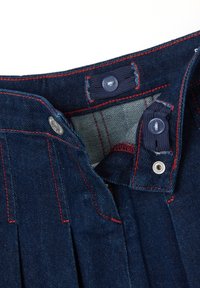 Dunkelblaue Denim-Hosen mit roter Naht, Knopfverschluss und gefaltetem Design. Das Innenfutter zeigt ein strukturiertes Stoffmuster.