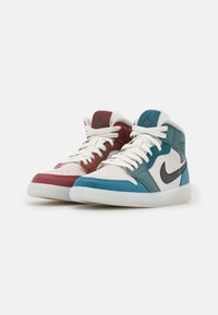 Mid-top sneakers met een kleurblokontwerp in rood, teal en crèmekleurig leer, witte veters en zwarte merkopdruk aan de zijkanten.