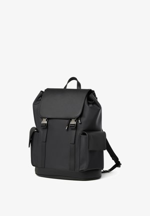 Schwarzer Leder-Rucksack mit Klappverschluss, zwei vorderen Metallverschlüssen, Seitentaschen und verstellbaren Schultergurten vor weißem Hintergrund.
