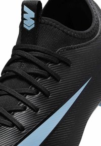 Chaussure de sport noire texturée avec un swoosh bleu clair sur le côté, des lacets noirs et une languette noire comportant un logo bleu clair.