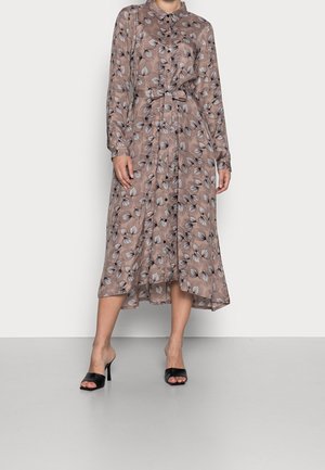 Robe marron à manches longues avec un motif de feuilles beige et noir, boutonnée devant, ceinture à la taille, et chaussures noires à talons hauts ouvertes.