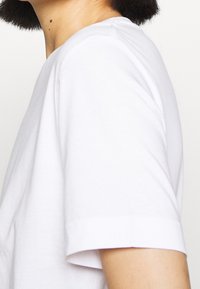 Witte katoenen T-shirt, korte mouwen, ronde hals, met een zachte structuur en een eenvoudig ontwerp zonder patronen of details.