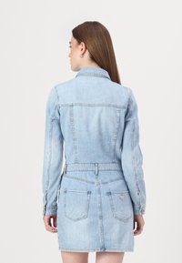 Svetlo modra denim jakna obleka z dolgimi rokavi, koničastim ovratnikom in oprijetim pasom. Ima dve zadnji žep, ter podrobnost logotipa na desni strani.