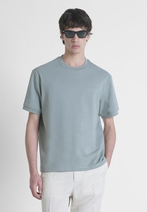 Svijetloplavi kratki rukav sweatshirt s okruglim izrezom. Ima suptilno izvezeno logotip na prsima i glatku, meku teksturu.