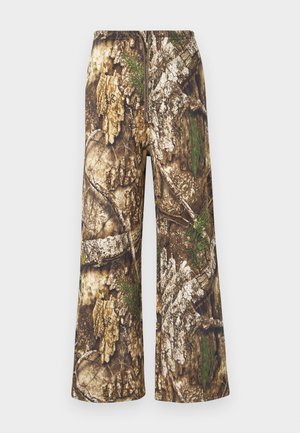 Pantalones camuflaje con diseño de pierna ancha. Presentan una mezcla de marrones terrosos, verdes y patrones texturizados que recuerdan a la corteza de los árboles y el follaje.