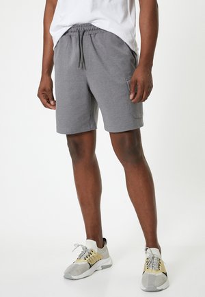 Grijze katoenen shorts met een elastische tailleband en een trekkoord, voorzien van zijzakken en een comfortabele pasvorm, gecombineerd met lichte sneakers.