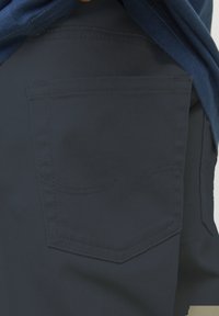 Shorts bleu marine avec une texture lisse, dotés d'une poche arrière avec des détails de couture courbés et d'une taille standard.
