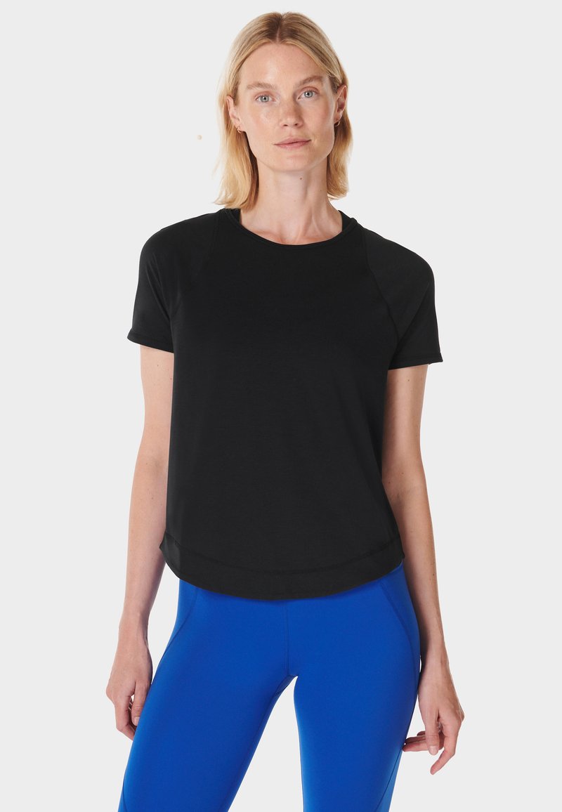 Zwart T-shirt met korte mouwen, ronde hals en een ontspannen pasvorm. Voorzien van raglanmouwen en een gebogen zoom, gemaakt van zachte stof.