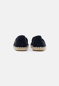 Navy blue espadrilles with a soft suede upper, braided jute sole, and stitching accents along the edge. Open back design for easy wear.